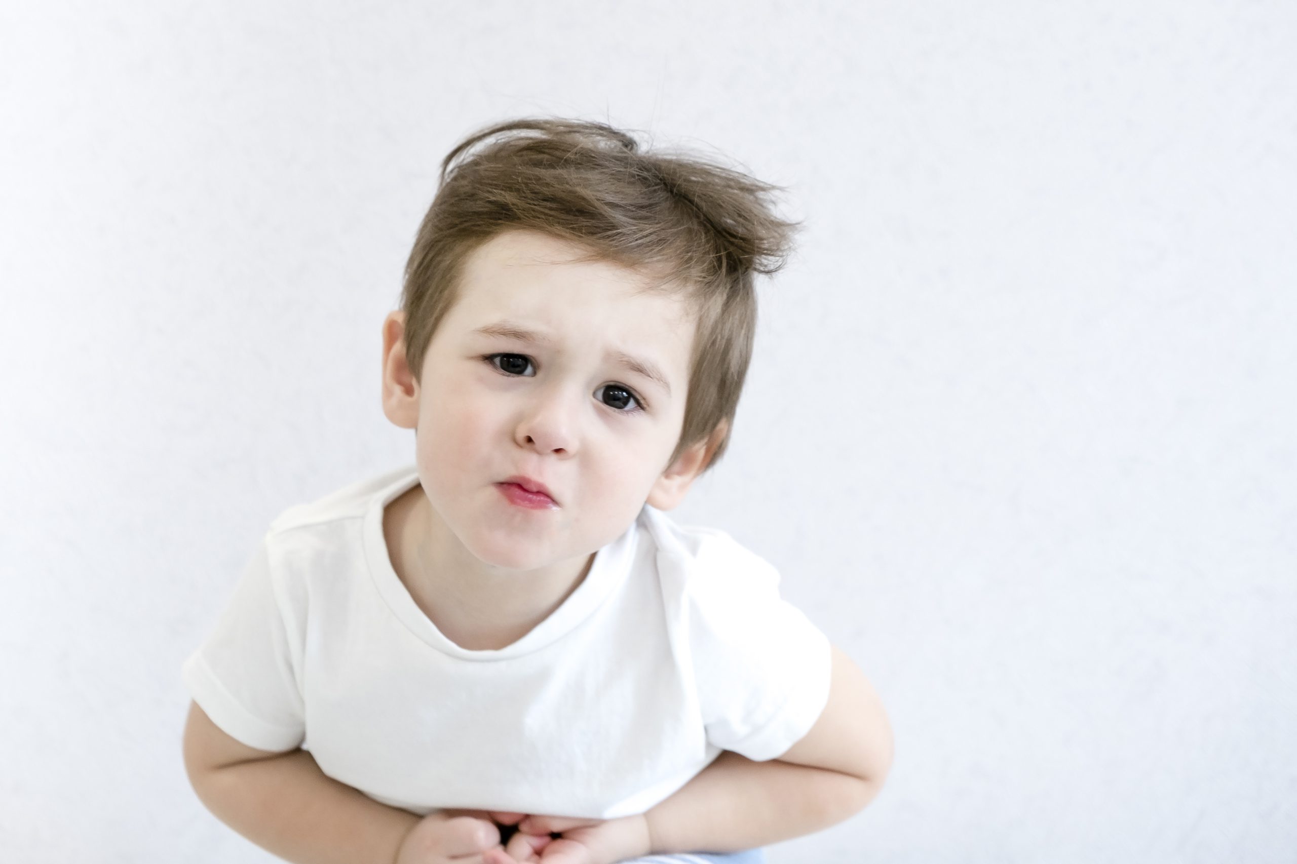 Caucasian little boy with stomach ache, child holding his hands on his belly. Stomach ache child stock image.